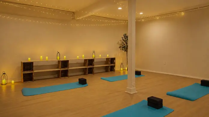 Yoga studio at Recovery Beach with teal mats, string lights, and candlelit decor