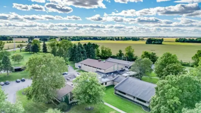 Aerial view of the Woodland Grove Recovery campus with multiple buildings, green space, trees, and surrounding fields.