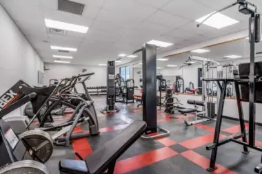 Fitness center at Woodland Grove Recovery with cardio machines, weight equipment, benches, and strength training equipment.