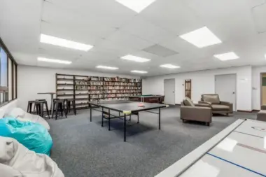 Woodland Grove Recovery recreation room featuring a ping pong table, pool table, bookshelves, and lounge seating.