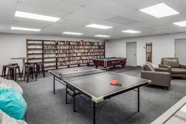 Recreation room at Woodland Grove Recovery with a pool table, lounge seating, bookshelves, and game tables.