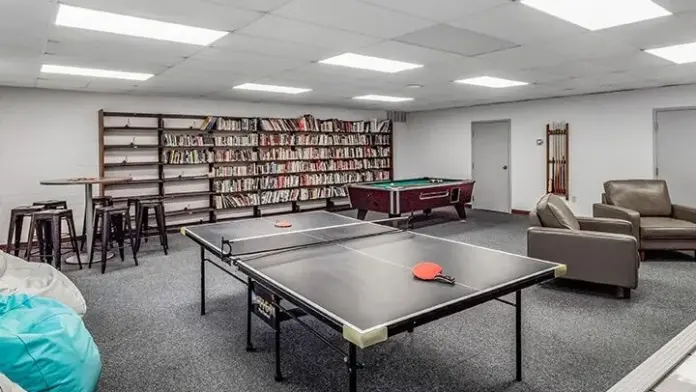 Recreation room at Woodland Grove Recovery with a pool table, lounge seating, bookshelves, and game tables.