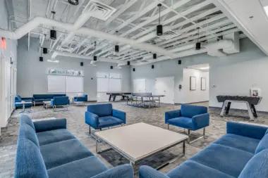 Spacious activity room with blue chairs, a ping pong table, and a foosball table at Boca Recovery Center Huntington.