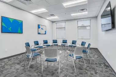 Group therapy room at Boca Recovery Center Huntington with blue chairs and modern artwork.