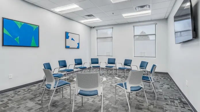 Group therapy room at Boca Recovery Center Huntington with blue chairs and modern artwork.