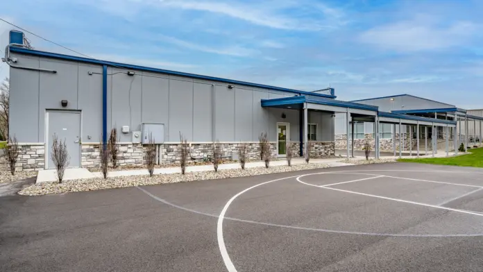 Outdoor basketball court at Boca Recovery Center Huntington, with a concrete area and surrounding landscaping.