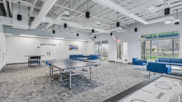 Recreational room at Boca Recovery Center Huntington featuring ping pong and foosball tables, comfortable seating, and large windows.