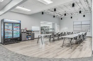 Modern dining area at Boca Recovery Center Huntington with a snack station, seating, and a beverage fridge.