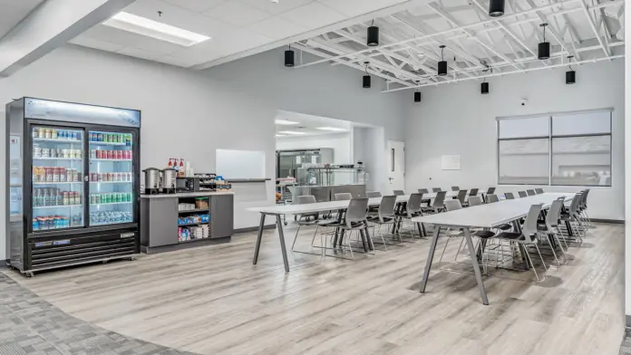Modern dining area at Boca Recovery Center Huntington with a snack station, seating, and a beverage fridge.
