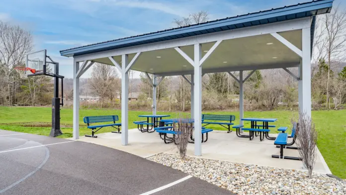 Outdoor basketball court with a covered seating area and picnic tables at Boca Recovery Center Huntington.