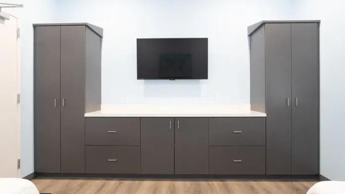 Patient room at Boca Recovery Center Huntington, complete with storage cabinets and a wall-mounted television.