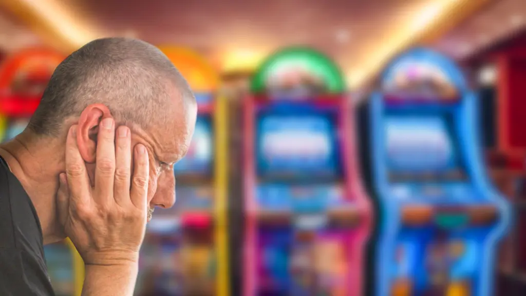 distressed man sitting in front of a line of slot machines