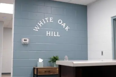 Alt Text: Interior view of a reception area with a gray textured wall featuring the white arched text 