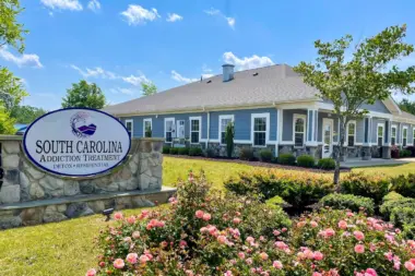 South Carolina Addiction Treatment center exterior with sign and blooming rose bushes. The sign reads 