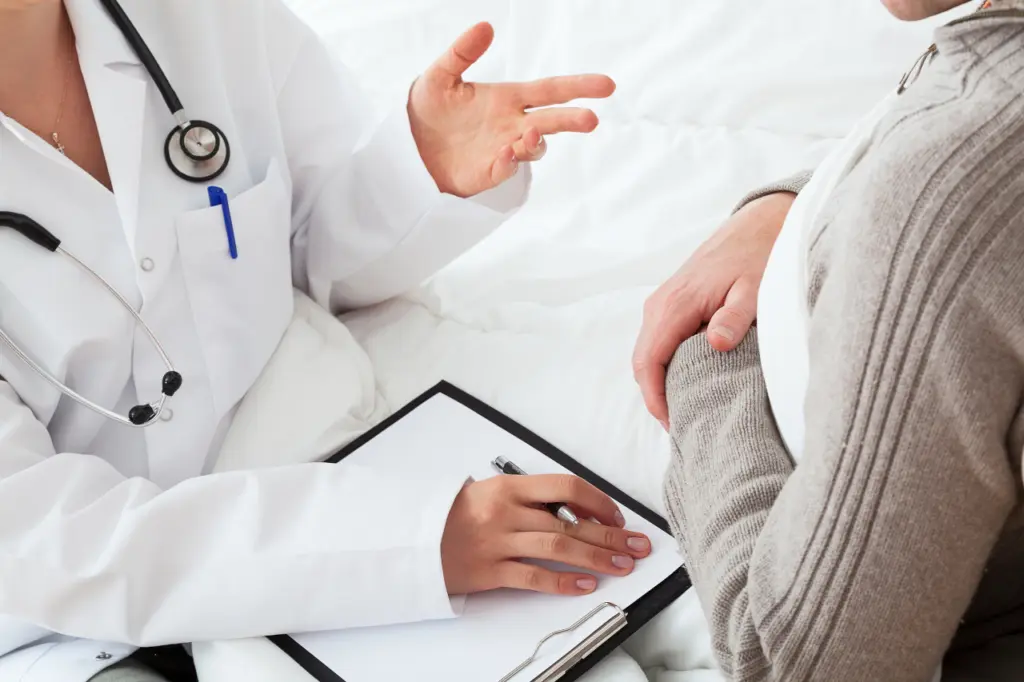 A doctor speaks with a patient sitting across from them at a desk