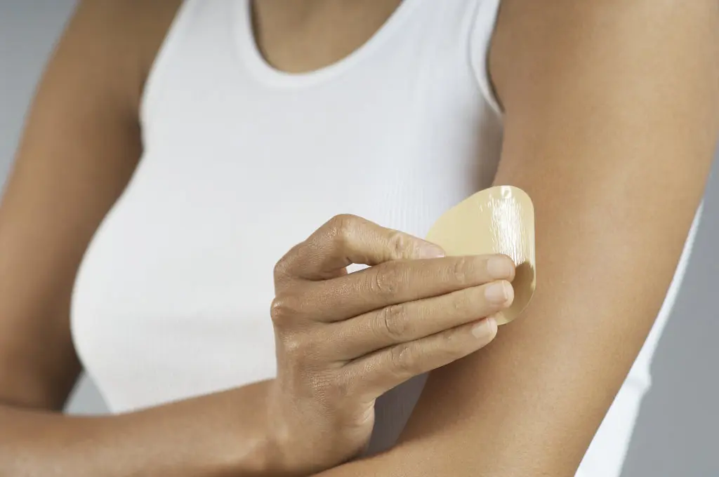 A woman applies a nicotine patch to her arm