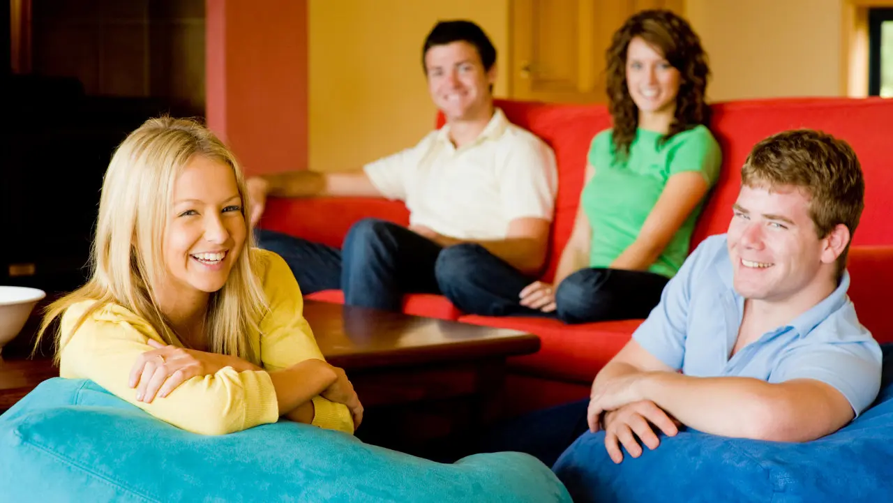 A group of smiling people hanging out in a sober living home