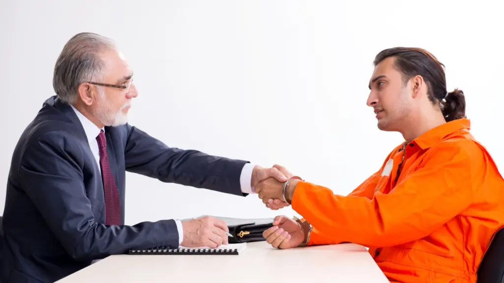 An inmate shakes hands with an older man, likely a parole or detention officer
