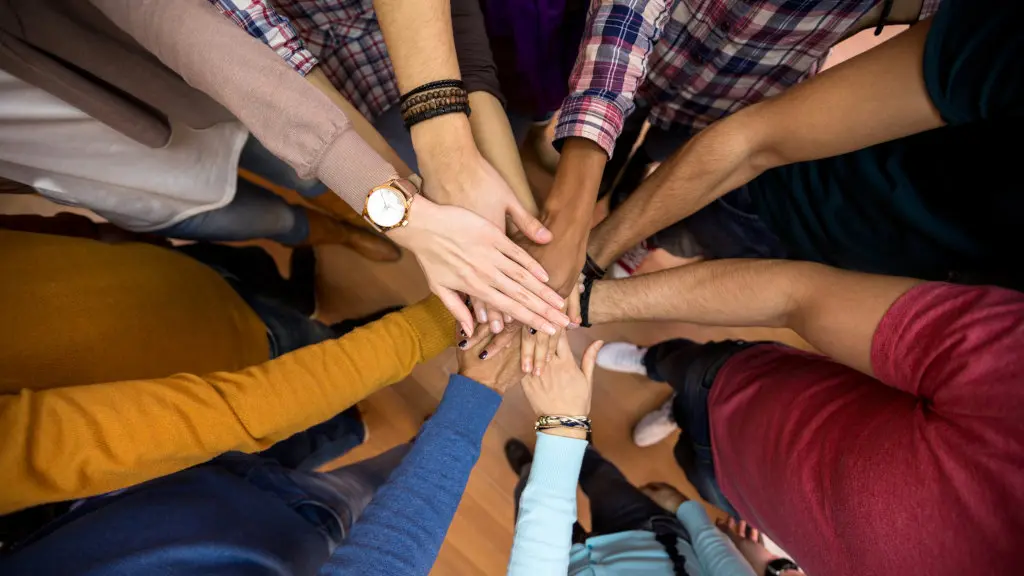A diverse selection of people join hands together in the center