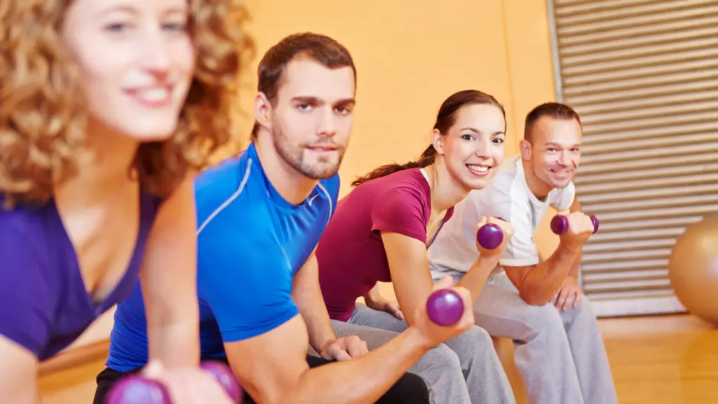 A few smiling people lifting weights as they participate in an aftercare program