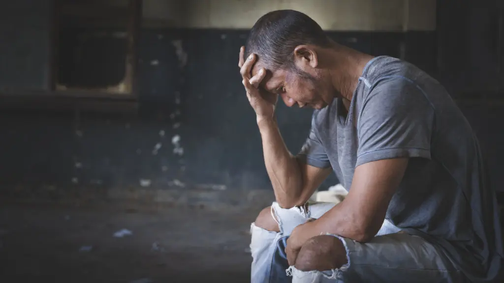 A man clutches his forehead, suffering from Alcohol Withdrawal Syndrome (AWS)