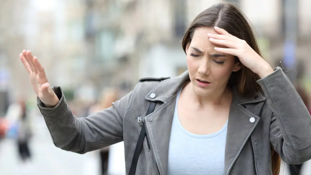 A woman clutches her head as alcohol withdrawal fatigue affects her body