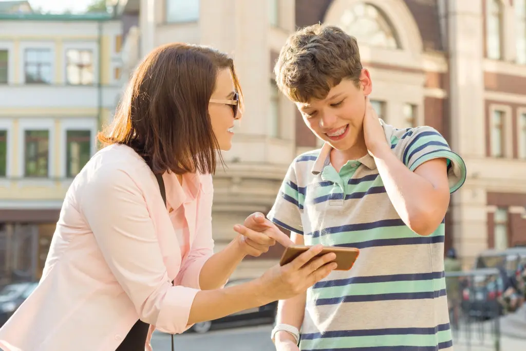 A mother shows her son how to use a smartphone