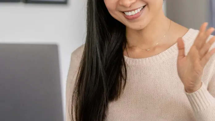 A woman waves to her doctor through a telehealth call