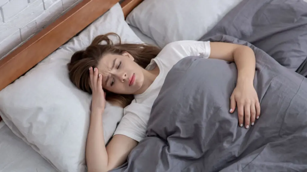 a woman laying in bed clutches her head. Learn more about xylazine withdrawal here.