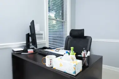 Interior office desk with computer setup, office supplies, window blinds, and clean minimalist design