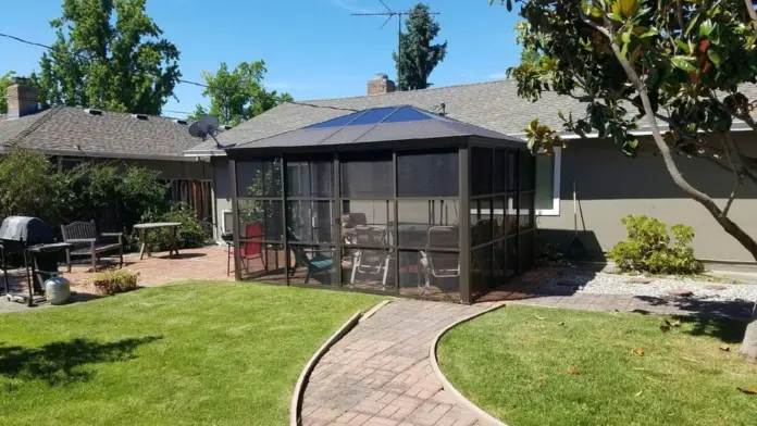 Outdoor patio area featuring screened pavilion, brick pathway, manicured lawn, and seating areas