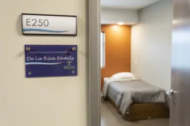 Doorway showing room number E250 and bedroom interior with bed and orange wall