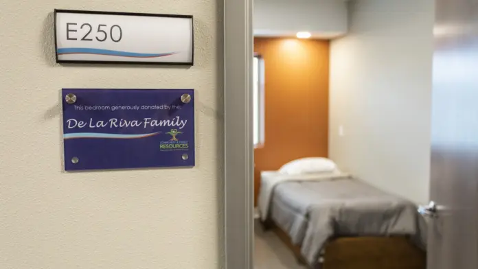 Doorway showing room number E250 and bedroom interior with bed and orange wall