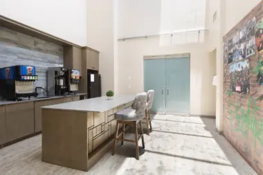 Interior break room with coffee station, counter seating, brick accent wall, and community photos