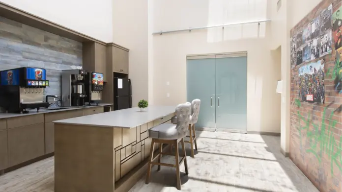 Interior break room with coffee station, counter seating, brick accent wall, and community photos