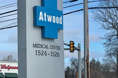 Exterior street signage for Atwood Medical Center at 1524-1526 with blue cross symbol and address marking