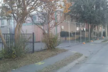 Exterior view of brick treatment facility with metal security fencing, concrete sidewalk, and gated entrance.
