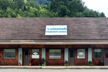 Exterior view of single-story facility with shingled roof, wood siding, windows, and Crossroads Treatment Centers sign