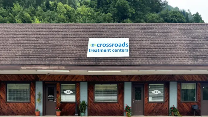 Exterior view of single-story facility with shingled roof, wood siding, windows, and Crossroads Treatment Centers sign