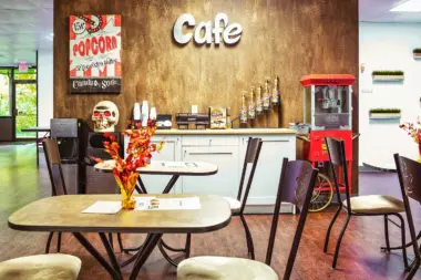 Interior cafe space with signage, popcorn machine, coffee counter, seating tables, and decorative wall art