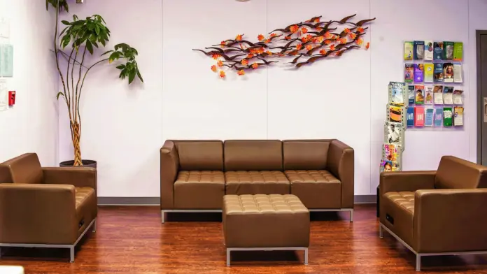 Interior lounge with brown leather seating, decorative artwork, plants, wood flooring, and purple accent walls