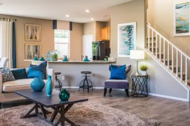 Interior common gathering space with stairs, kitchen area, seating, artwork, and natural window lighting