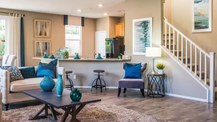 Interior common gathering space with stairs, kitchen area, seating, artwork, and natural window lighting