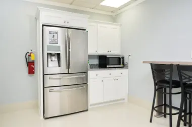 Interior kitchen space with multi-door refrigerator, white cabinetry, dining seating, and overhead skylight