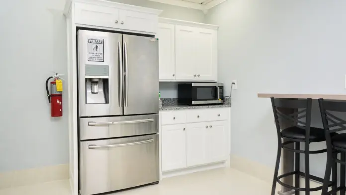 Interior kitchen space with multi-door refrigerator, white cabinetry, dining seating, and overhead skylight