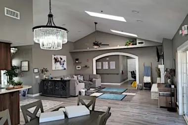 Interior reception space with high ceiling, chandelier, sectional seating, decorative arch, wood flooring, and open layout.