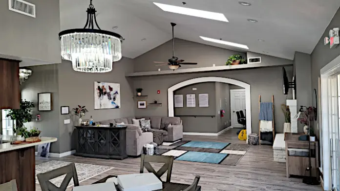 Interior reception space with high ceiling, chandelier, sectional seating, decorative arch, wood flooring, and open layout.