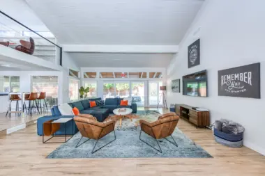 Interior lounge with blue sectional sofa, brown leather chairs, large windows, and modern fireplace