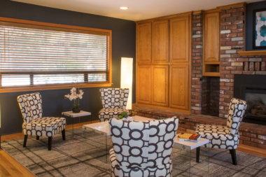 Interior common area with geometric patterned chairs, fireplace, dark accent wall, and wooden cabinetry