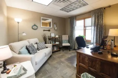 Interior counseling office with comfortable seating, desk workspace, natural lighting, and professional decor
